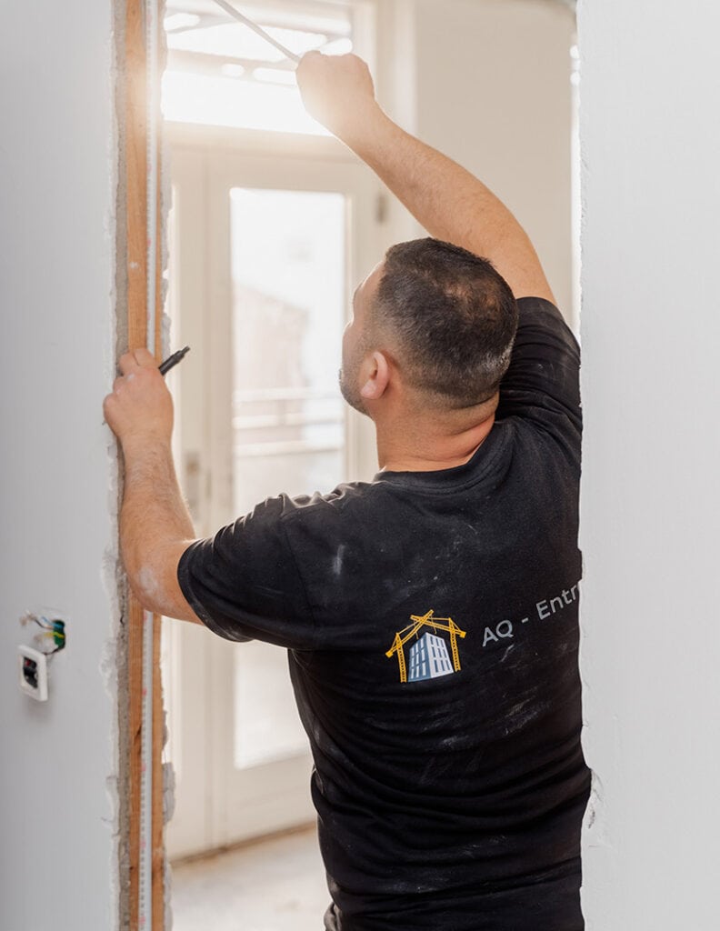 Tømrer tilpasser dørkarm i en lejlighed under renovering.
